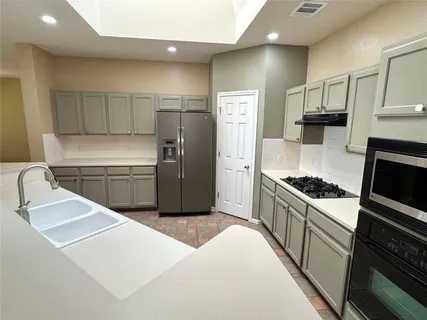 a kitchen with granite countertop a sink stove and refrigerator