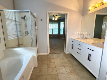 a bathroom with a bathtub and a double vanity sink mirror