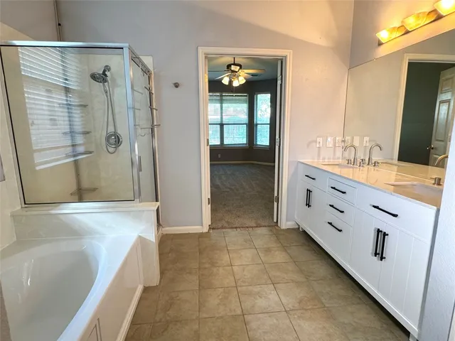 a bathroom with a bathtub and a double vanity sink mirror