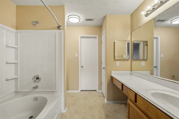a bathroom with a granite countertop sink a mirror a bathtub and shower