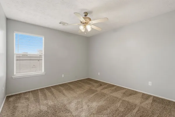 an empty room with a window and a ceiling fan