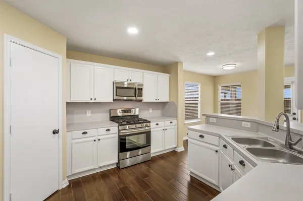 a kitchen with granite countertop white cabinets and stainless steel appliances