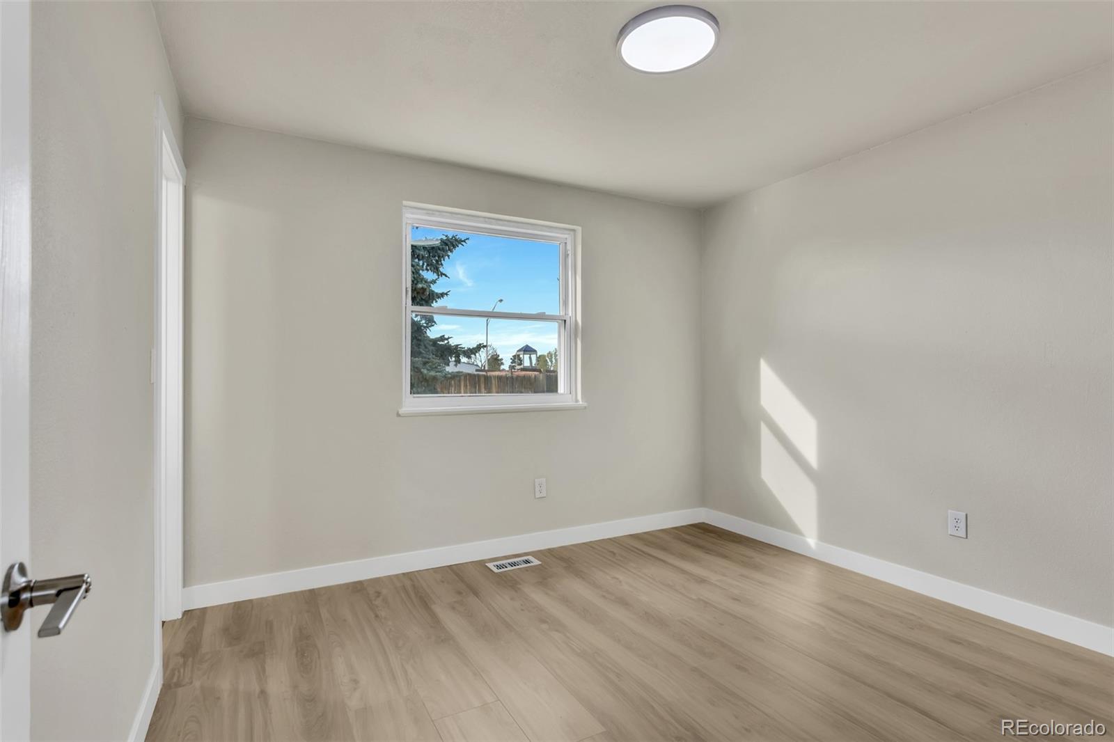 2787 South Helena Way Aurora, CO 80013 - Photo 14 of 26 an empty room with wooden floor and windows
