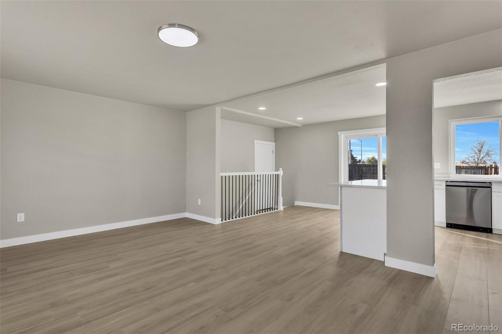 2787 South Helena Way Aurora, CO 80013 - Photo 3 of 26 an empty room with wooden floor and kitchen view