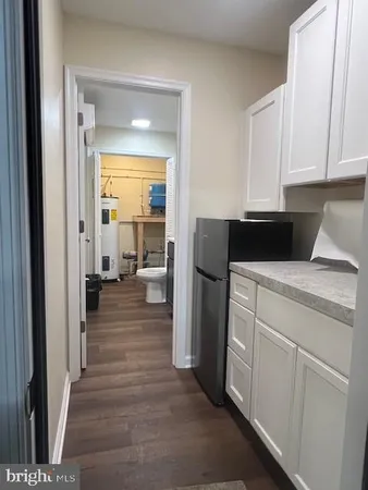 a kitchen with a refrigerator a stove top oven and white cabinets