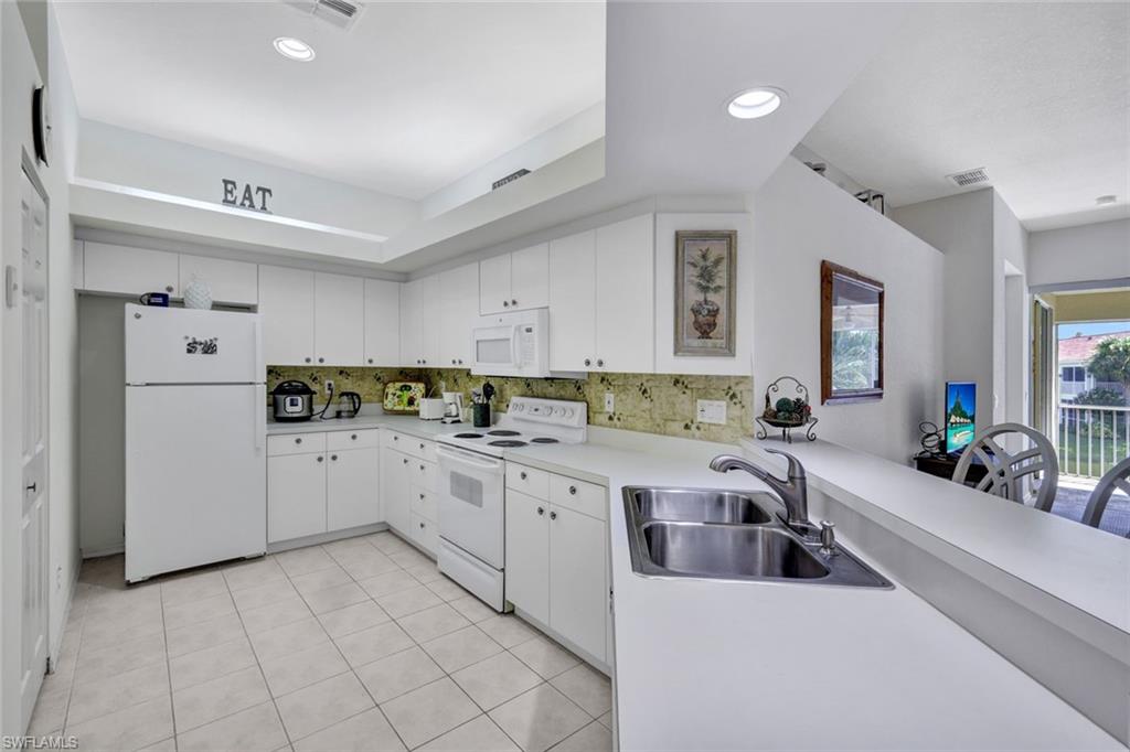 10711 Halfmoon Shoal Road, Unit 203 Estero, FL 34135 - Photo 11 of 25 a large white kitchen with cabinets and window