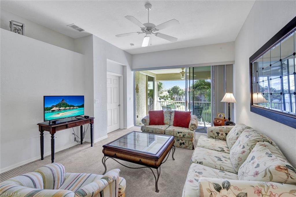 10711 Halfmoon Shoal Road, Unit 203 Estero, FL 34135 - Photo 5 of 25 a living room with furniture a flat screen tv and a large window
