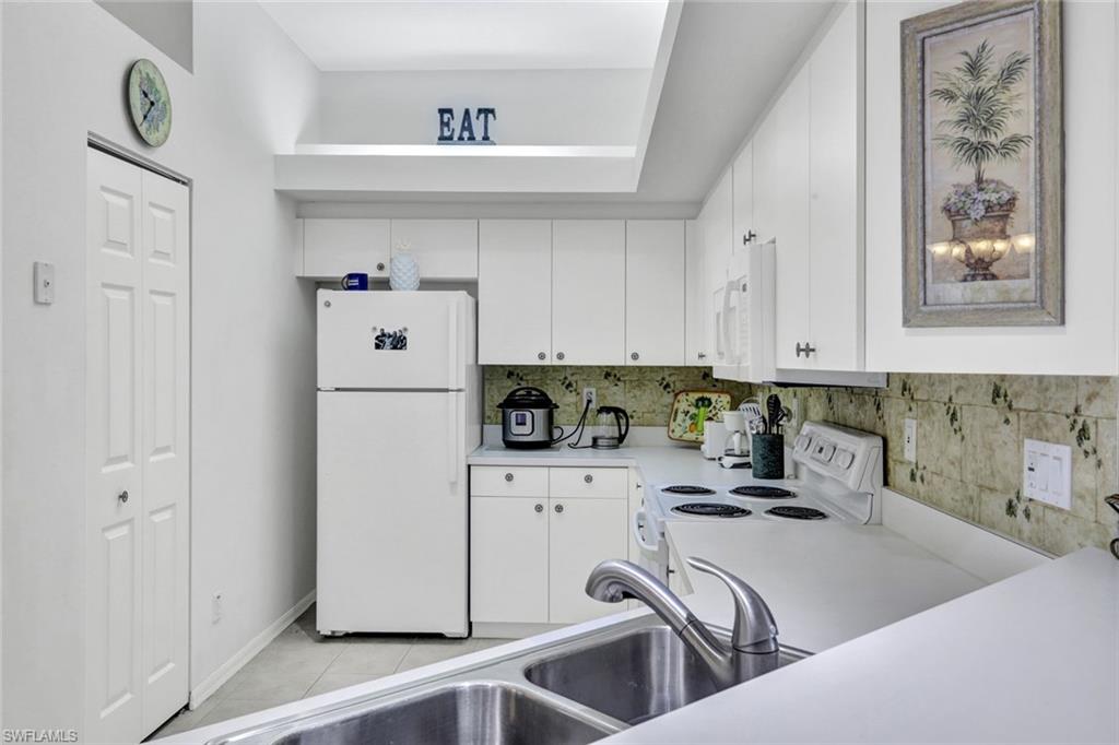10711 Halfmoon Shoal Road, Unit 203 Estero, FL 34135 - Photo 9 of 25 a kitchen with white cabinets and white appliances