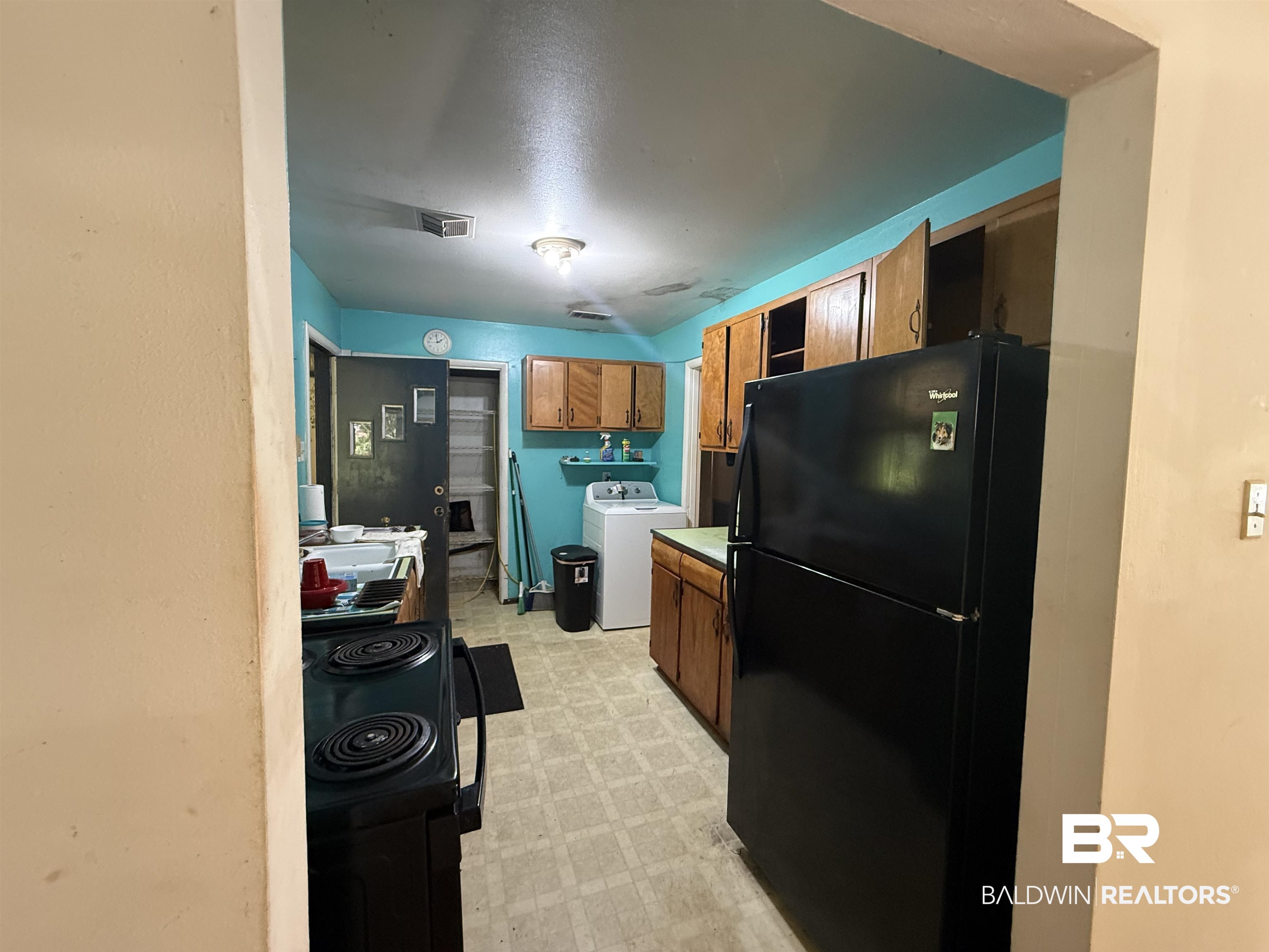 711 Wilshire Road Mobile, AL 36609 - Photo 4 of 11 Kitchen featuring wood cabinetry, a black electric range, and a black refrigerator