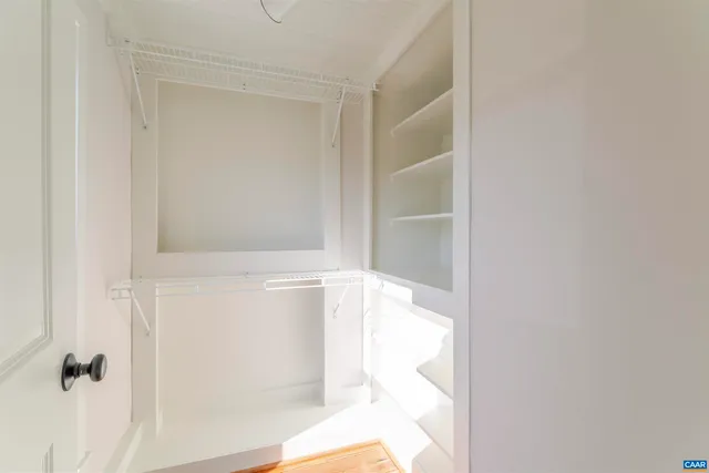 a view of a hallway with wooden floor and a bathroom