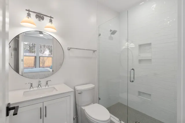 a bathroom with a toilet sink vanity granite and shower