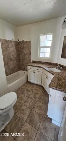 a bathroom with a granite countertop sink a toilet and bathtub