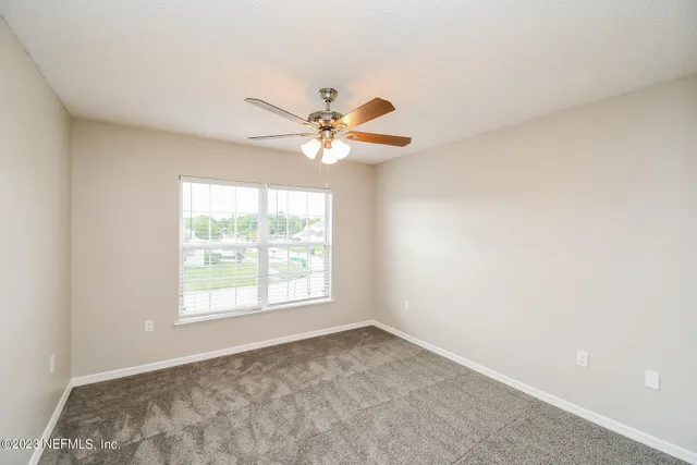 an empty room with a window and a fan