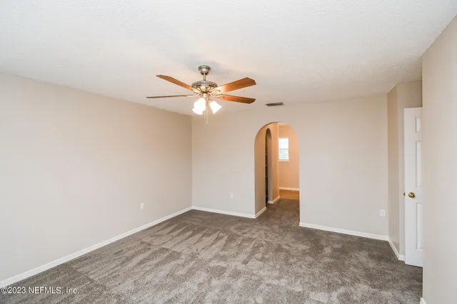 an empty room with closet and a chandelier fan