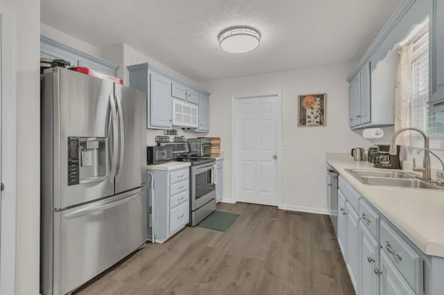 a kitchen with a refrigerator a sink and dishwasher with wooden floor