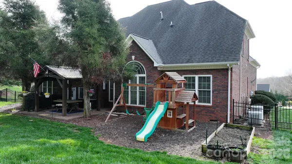 a view of a house with a backyard and a large tree