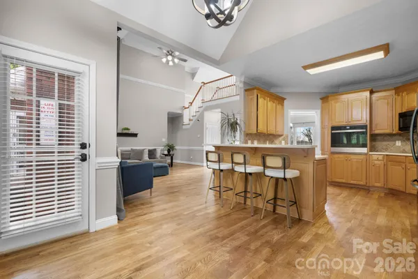a kitchen with stainless steel appliances kitchen island granite countertop a table chairs sink and cabinets