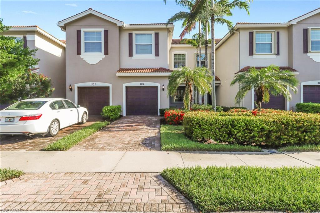 View of front of home with stucco siding, driveway, an attached garage, and a tile roof