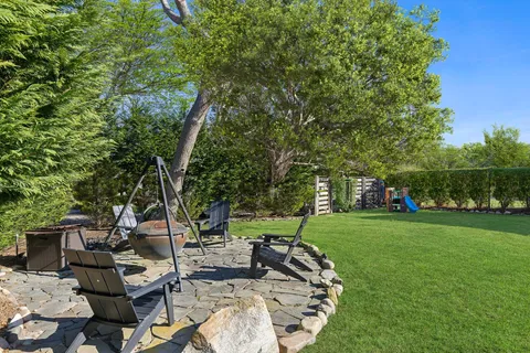 a view of a patio with table and chairs and a large tree
