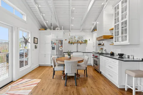 a kitchen with stainless steel appliances granite countertop a dining table chairs sink and cabinets