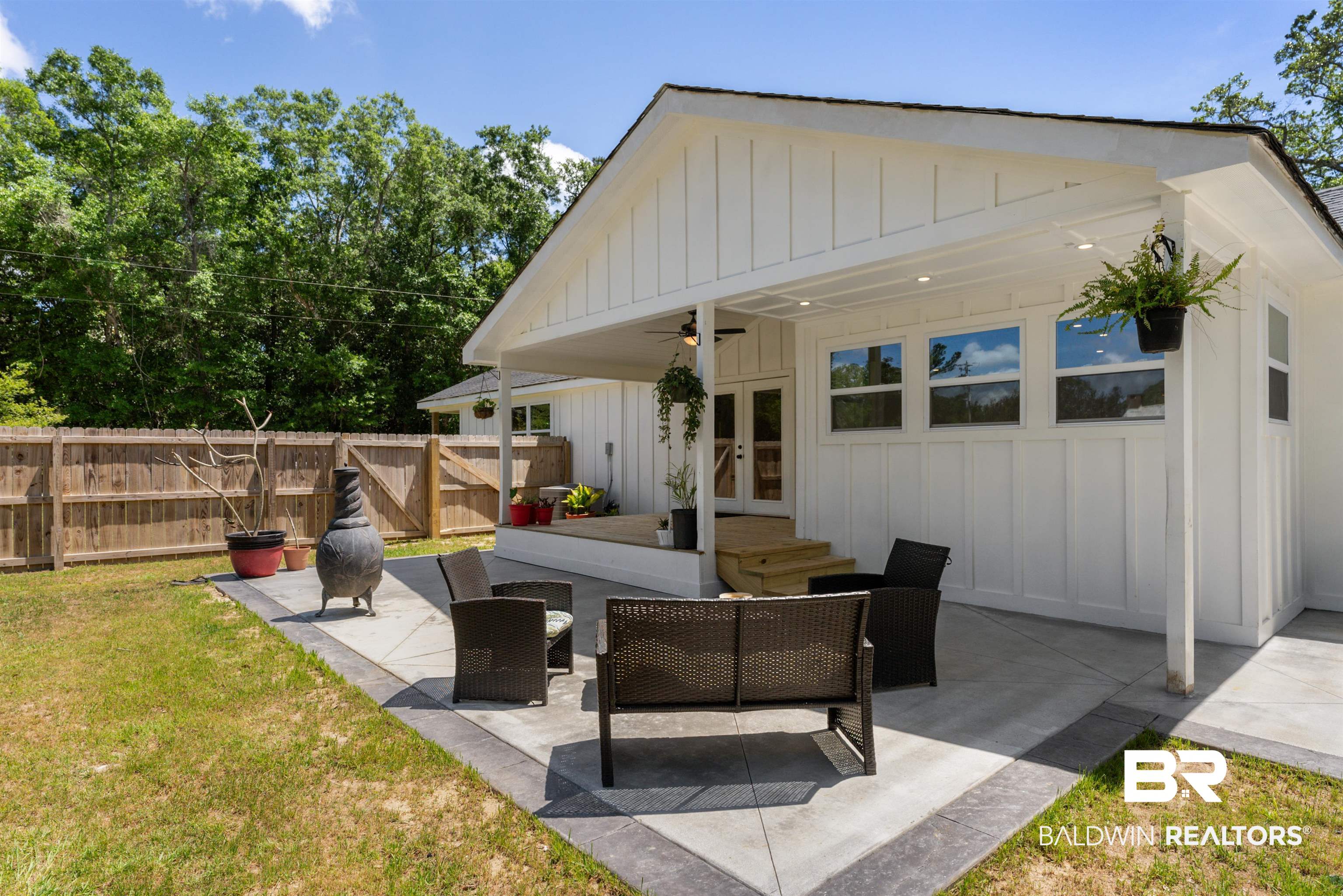 6447 Bemis Lane Bon Secour, AL 36511 - Photo 7 of 62 Expansive outdoor patio area featuring a covered porch, board and batten siding, multiple windows, and a wood privacy fence