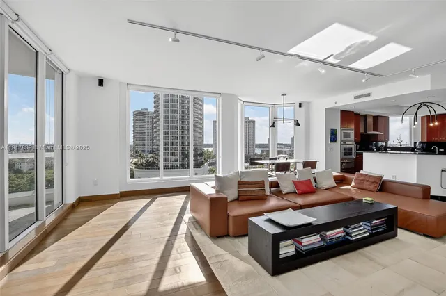 a living room with furniture large windows and wooden floor