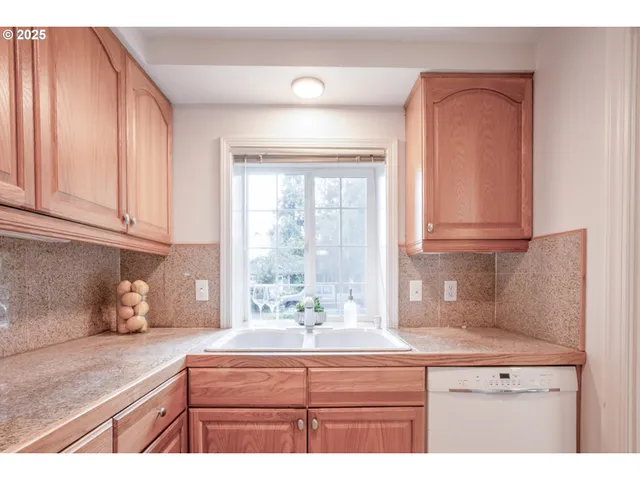 a kitchen with granite countertop a sink a window and cabinets