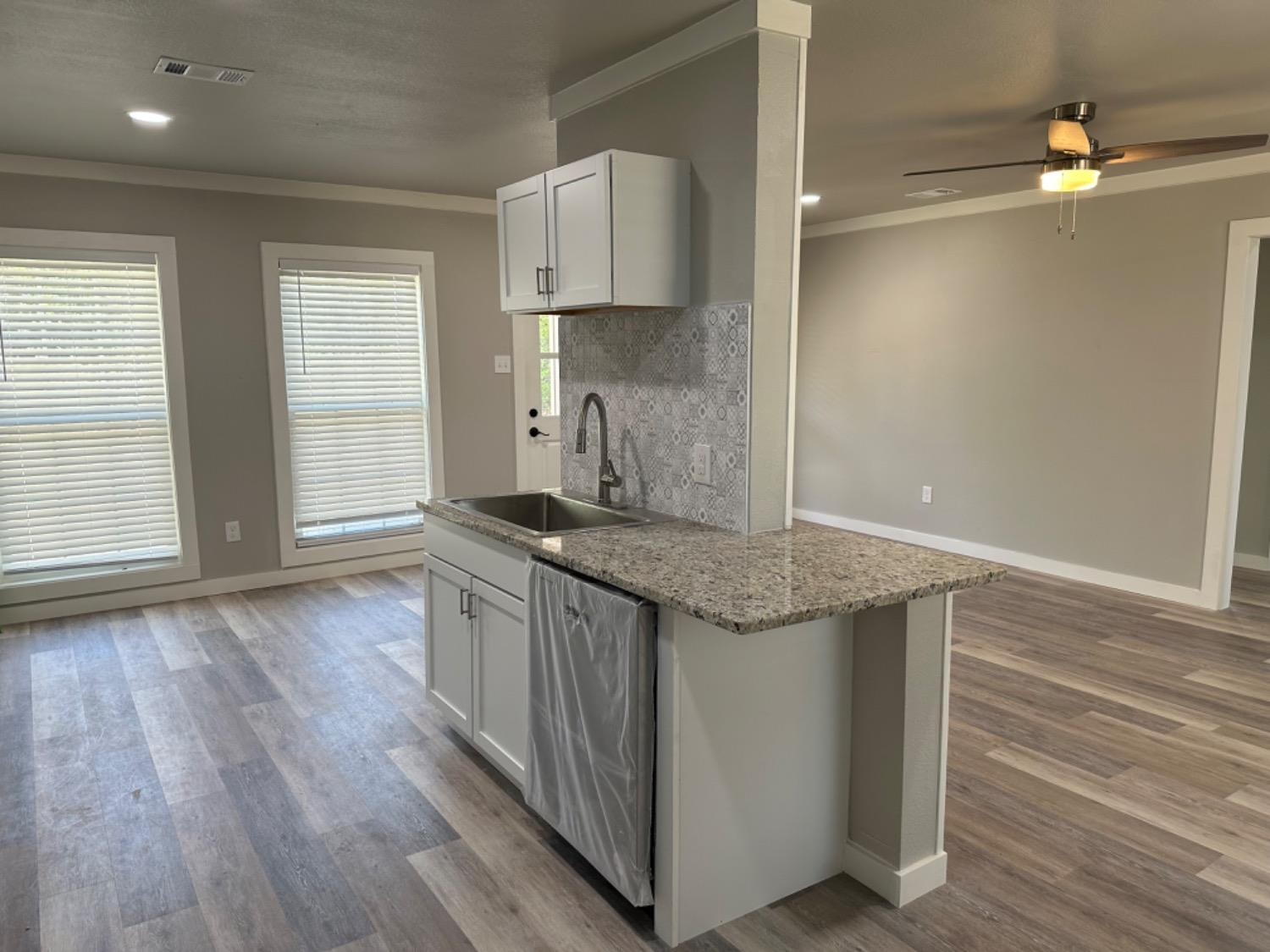 3408 29th Street Lubbock, TX 79410 - Photo 4 of 19 a kitchen with stainless steel appliances granite countertop a white cabinets and wooden floor