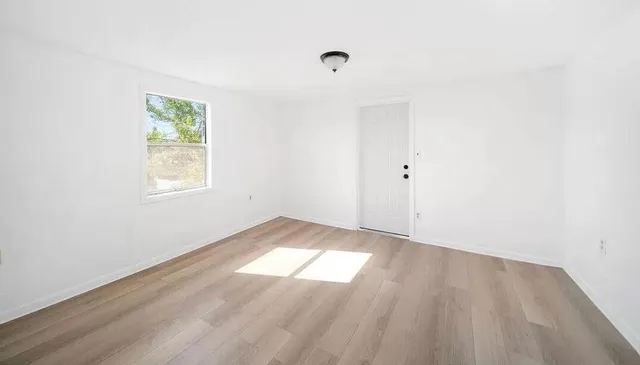 an empty room with wooden floor and windows