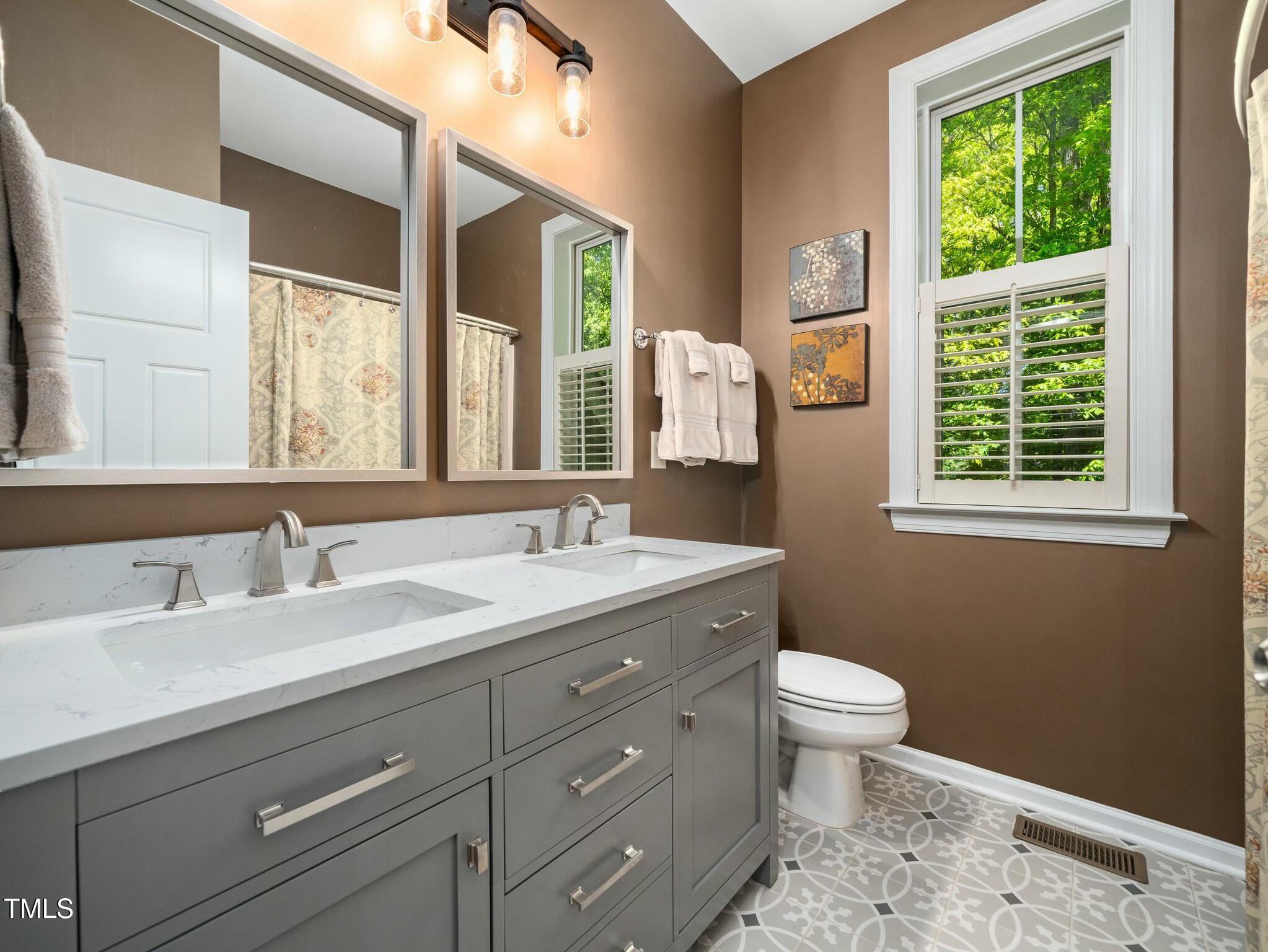 4210 Falls River Avenue Raleigh, NC 27614 - Photo 31 of 53 a bathroom with a granite countertop toilet a sink a mirror and a window