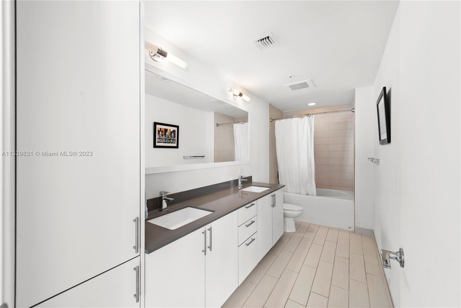 999 Southwest 1st Avenue, Unit 1811 Miami, FL 33130 - Photo 14 of 36 a spacious bathroom with a double vanity sink a mirror and a shower