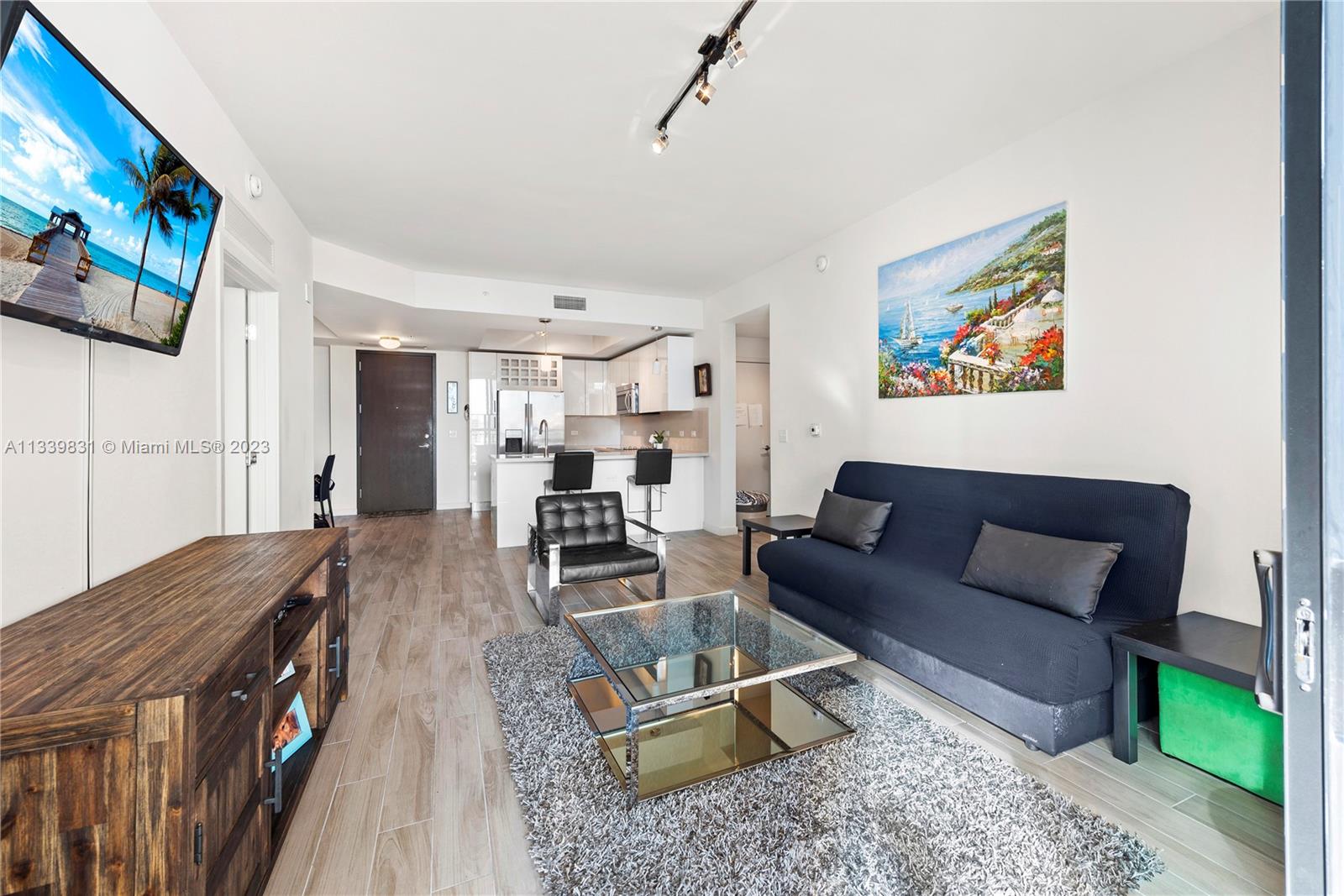 999 Southwest 1st Avenue, Unit 1811 Miami, FL 33130 - Photo 3 of 36 a living room with furniture a flat screen tv and a wall painting