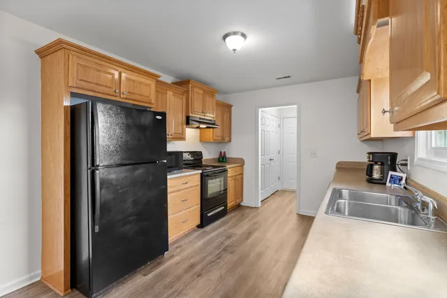 a kitchen with a refrigerator a stove top oven a sink and dishwasher with wooden floor