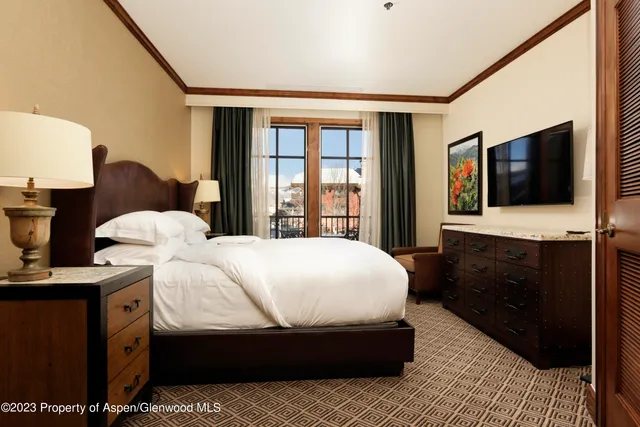 a bedroom with a bed and a flat tv screen on wall