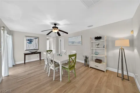 a dining room with wooden floor a chandelier a glass table and chairs
