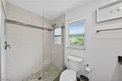 a bathroom with a granite countertop sink a toilet and a mirror