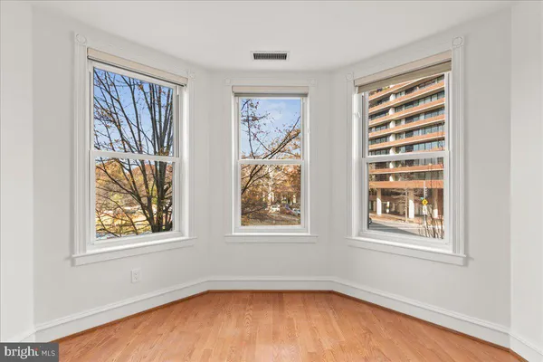 a view of an empty room with a window and wooden floor