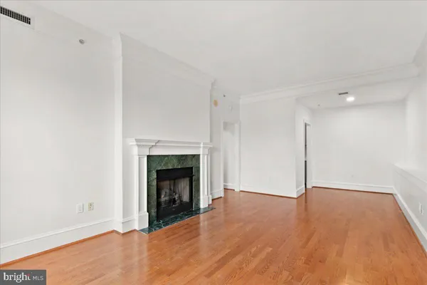 a view of an empty room with wooden floor fireplace and a window
