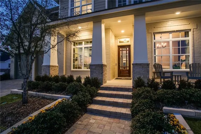 a front view of a house with plants and large trees