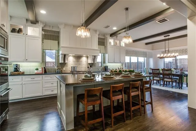 a kitchen with stainless steel appliances granite countertop table chairs stove and wooden floor