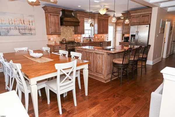 a dining hall with stainless steel appliances kitchen island granite countertop a dining table chairs and a kitchen view