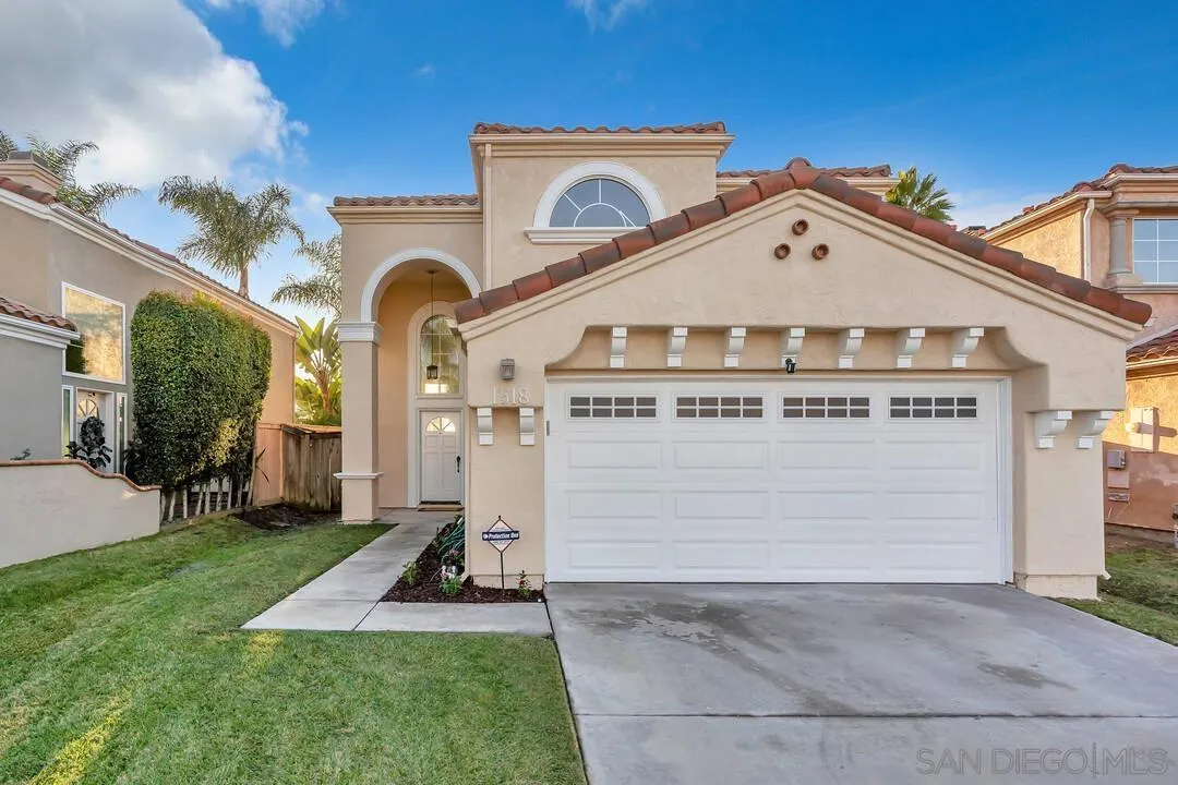 a view of a house with a small yard and a large tree