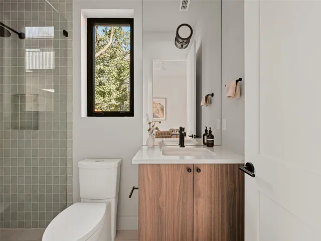 a bathroom with a granite countertop toilet sink and mirror