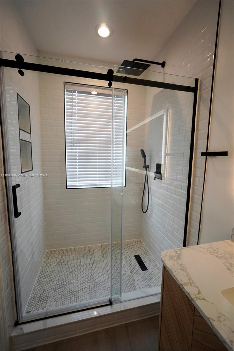 123 Harbors Way Boynton Beach, FL 33435 - Photo 33 of 38 a bathroom with a granite countertop sink a mirror a shower and vanity