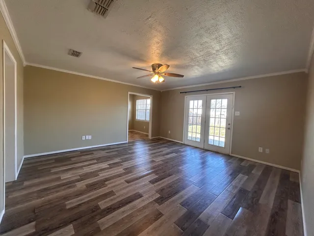 a view of an empty room with a window and wooden floor