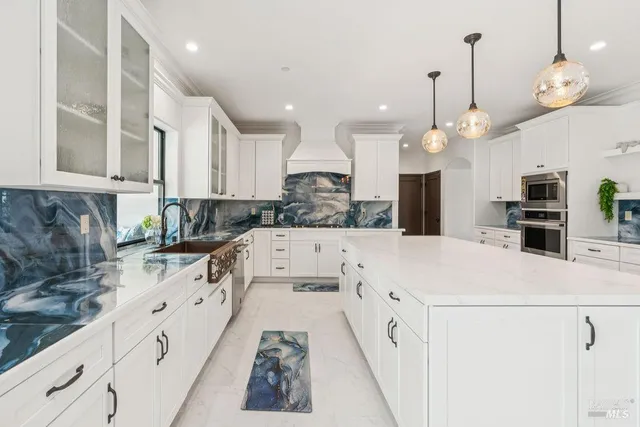 a kitchen with granite countertop a sink and a white wooden cabinets