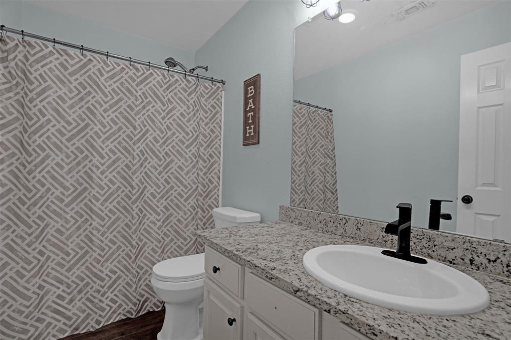 1005 Caleb Street Burleson, TX 76028 - Photo 22 of 31 a bathroom with a granite countertop toilet sink and mirror