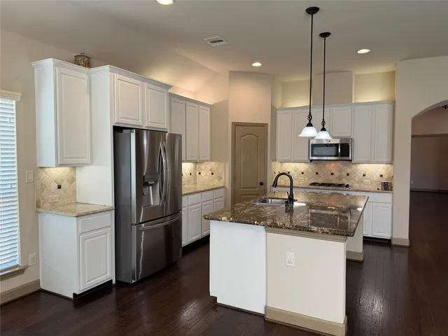 a kitchen with kitchen island a counter top space a refrigerator a sink and a stove