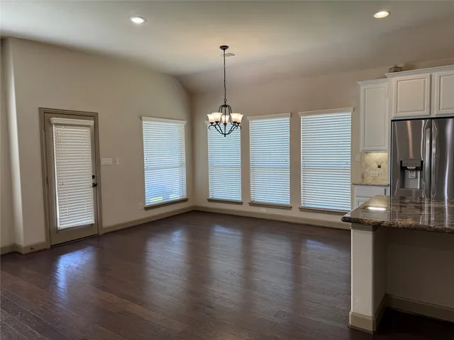 a view of a room with wooden floor kitchen view and windows