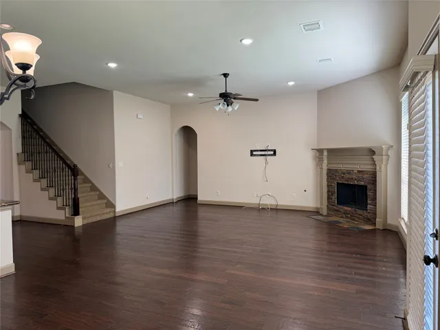 a view of an empty room with wooden floor fireplace and a window